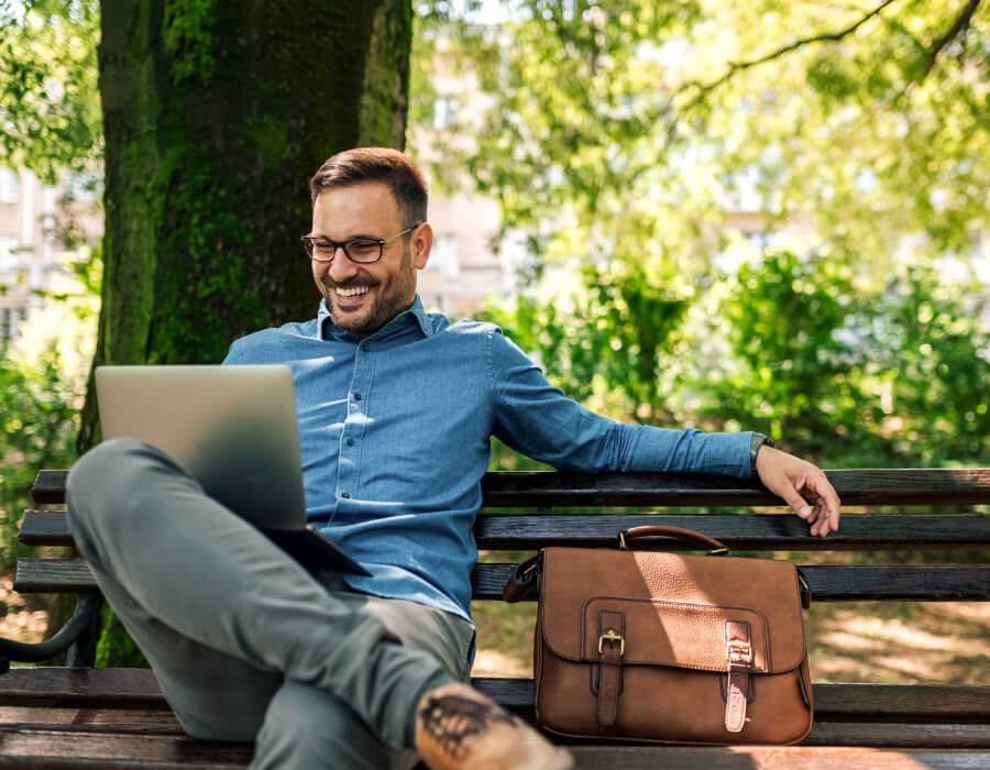 Grow your super, your way A professional businessman sitting in the park working on his laptop.