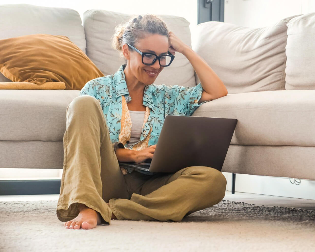 Privacy Policy A woman sitting on the floor working on her laptop.
