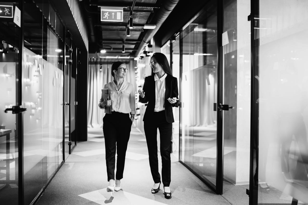 Successful female executive managers walking in corporate hallway