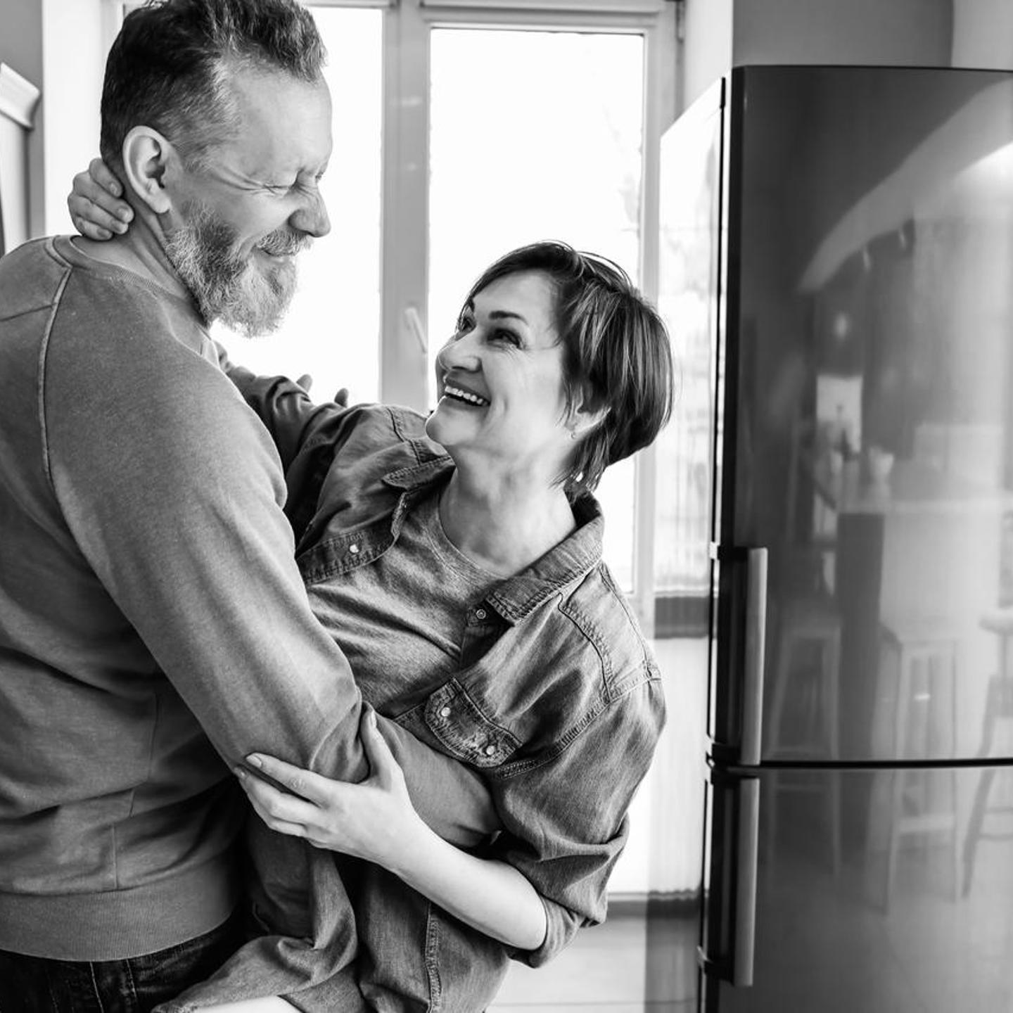 Smiling couple standing up and hugging in the kitchen